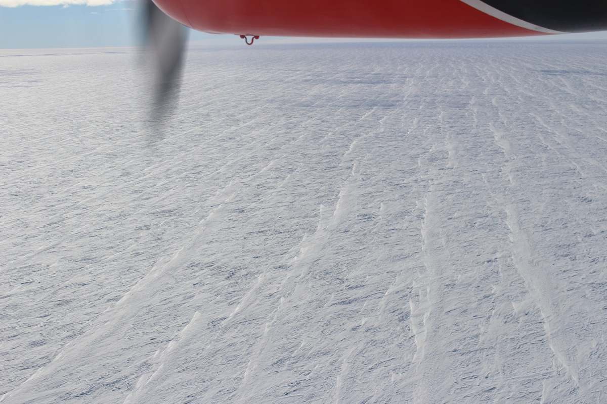 Длинные тонкие снежные дюны, покрывающие большую часть Антарктиды, легче увидеть сверху, чем с земли. Они формируются по направлению ветра / © Physics Today, Ghislain Picard.