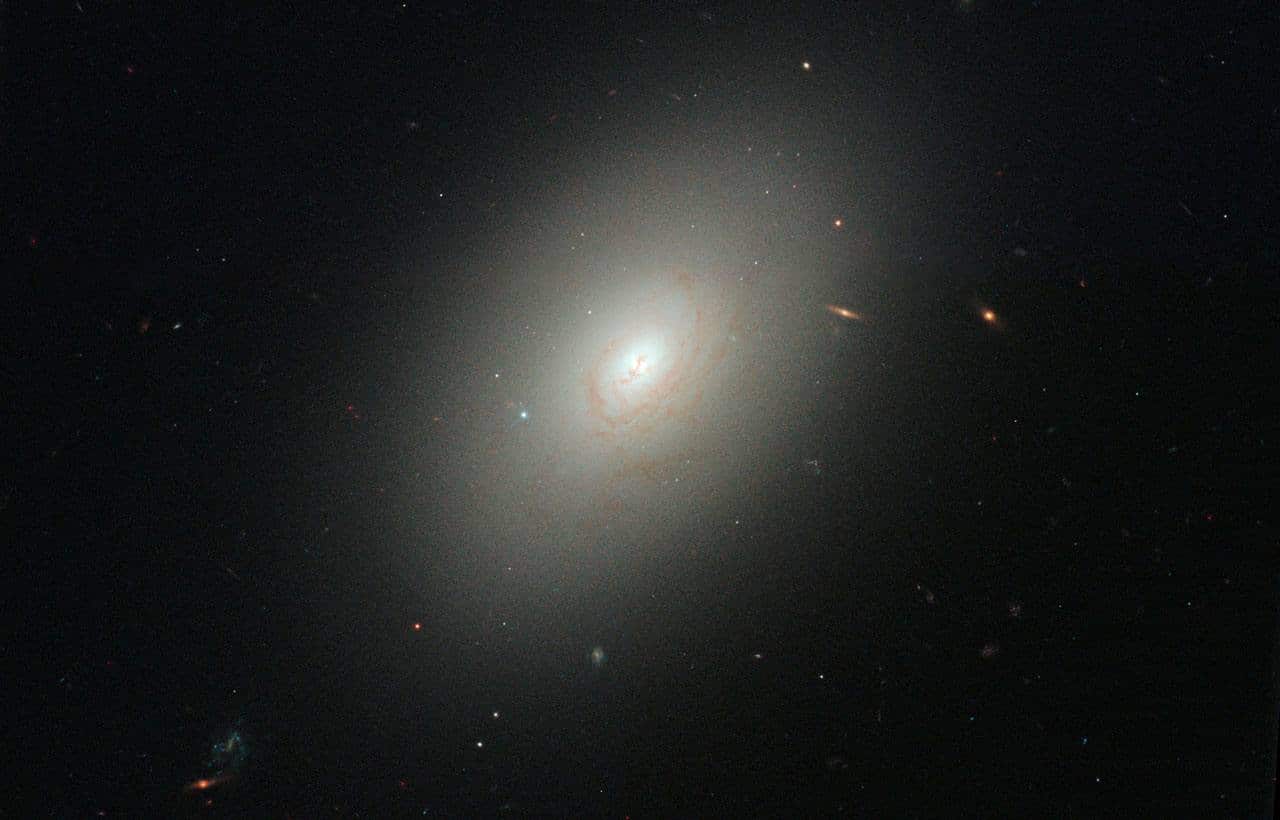 Эллиптическая галактика NGC 4150 в современной Вселенной, полная старых звезд, в которой произошла вспышка звездообразования из-за слияния с карликовой галактиой. Возможно, так древние потухшие массивные галактики наращивали свою массу / © NASA, ESA