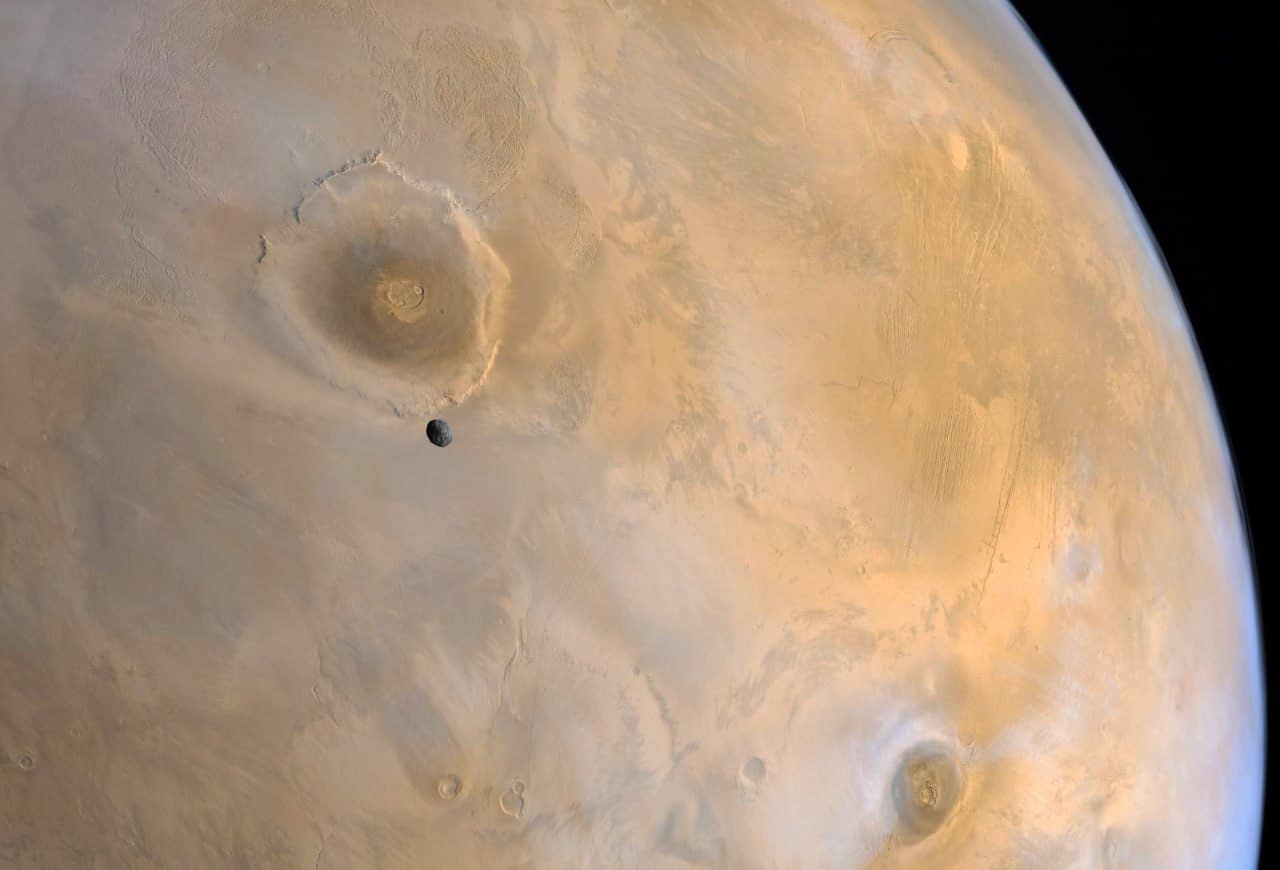 Поверхность Марса, на фоне Олимпа, самой высокой из всех известных гор,  видно спутник Марса Фобос, снимок с орбиты / © Wikimedia Commons, NASA